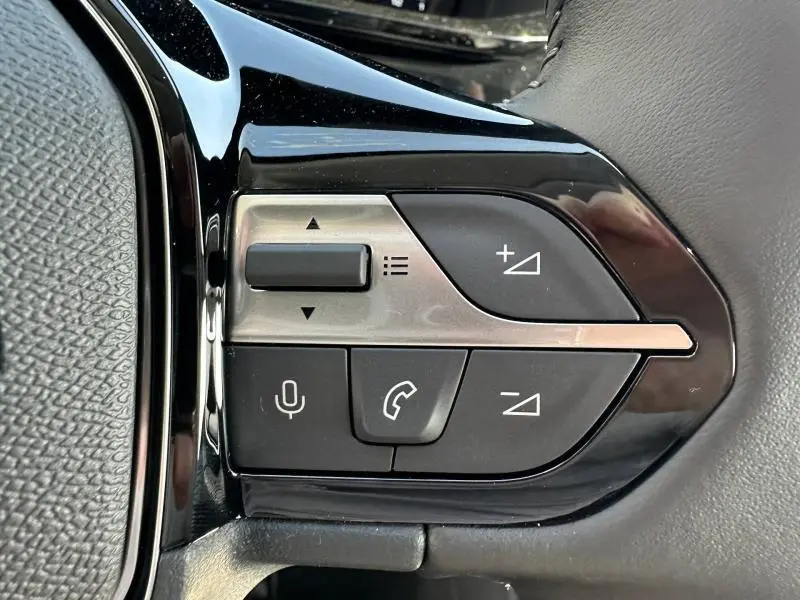 Gros plan sur les commandes multifonctions noires et argentées du volant côté gauche du Peugeot 308 gris Artense.