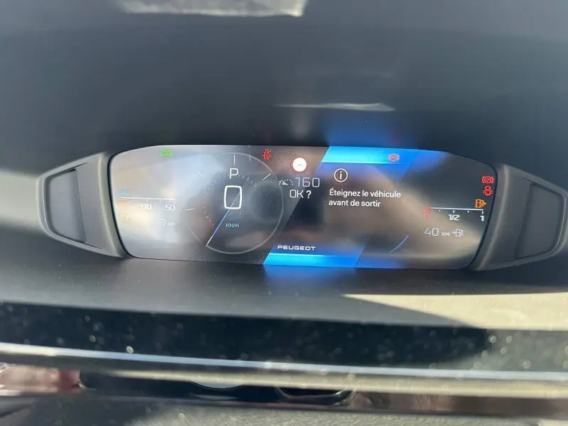 Tableau de bord numérique de Peugeot 308 2025 affichant la vitesse à 0 km/h et un message d'arrêt du véhicule.