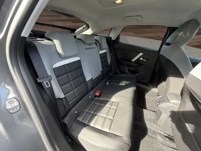 Vue intérieure arrière côté gauche de la Citroën C4 Hybrid 145 gris Mercury, sièges bicolores noir et gris avec surpiqûres.