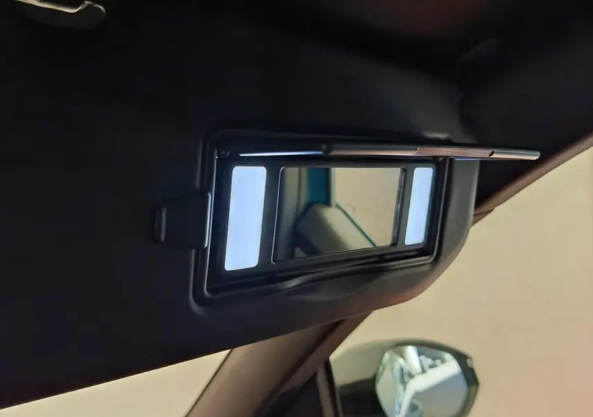 Détail du miroir de courtoisie éclairé sur le pare-soleil côté conducteur d’un Peugeot 3008 bleu.
