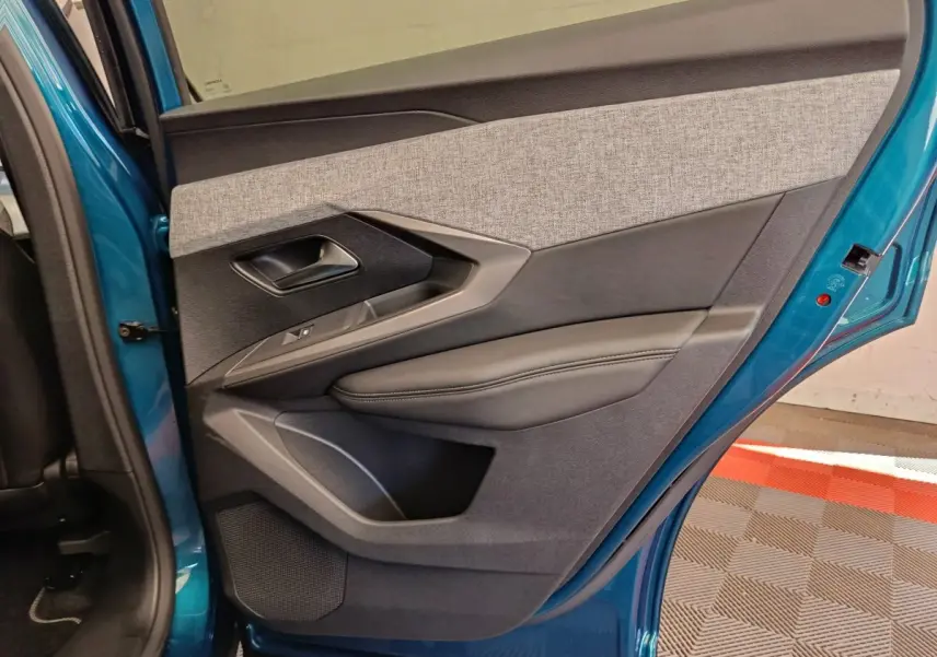 Vue intérieure de la porte arrière gauche bleu métallisé du Peugeot 3008 1.2 Hybrid 136 E-DCS6 GT avec garniture tissu et cuir.