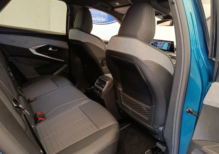 Vue intérieure arrière côté droit du Peugeot 3008 bleu 2025, sièges bi-matière et écran tactile avant visible.