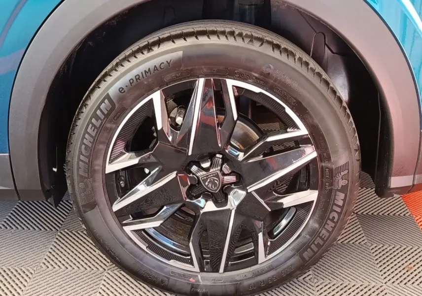 Gros plan sur la roue avant droite du Peugeot 3008 bleu, mettant en valeur la jante noire et argentée au design moderne.