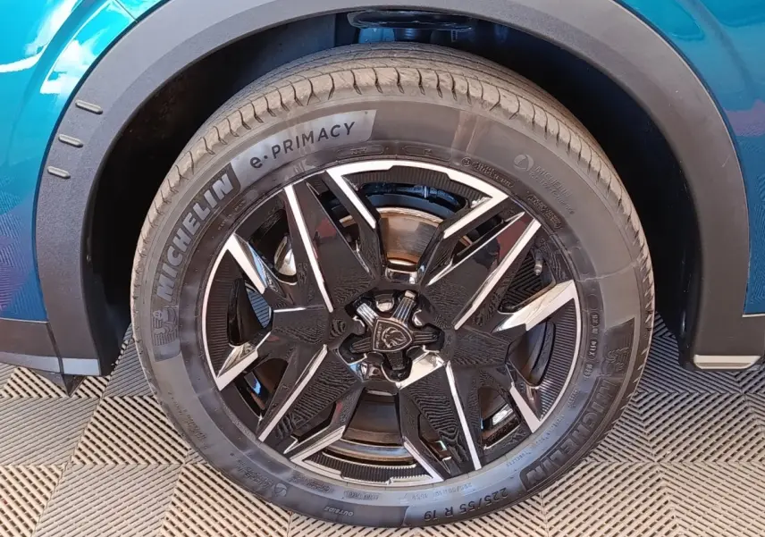 Gros plan sur la roue avant gauche du Peugeot 3008 bleu, mettant en valeur la jante noire et argentée au design moderne.