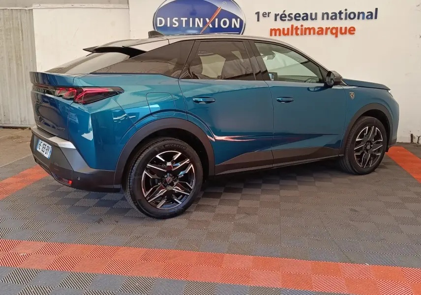 Vue 3/4 arrière droite du Peugeot 3008 bleu 2025 avec jantes noires et toit noir brillant.