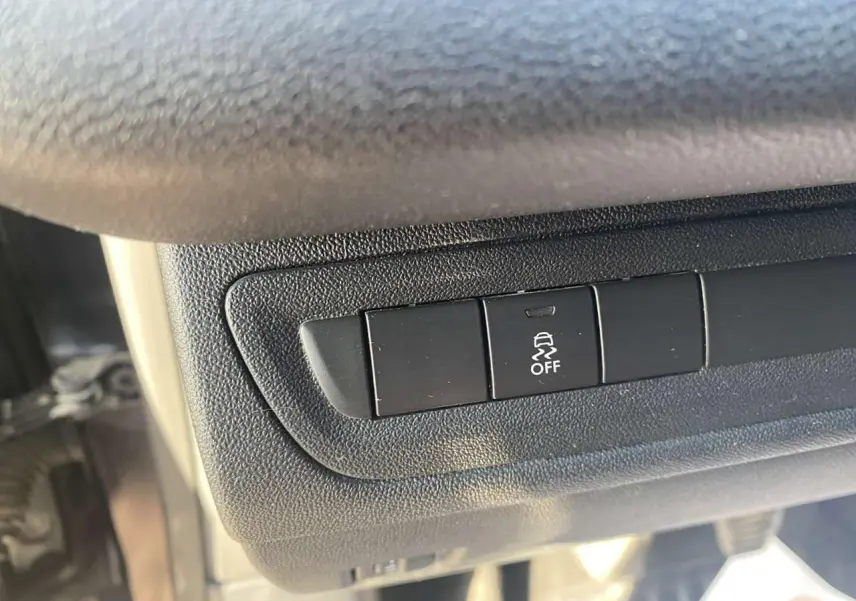 Gros plan sur le bouton de désactivation de l'ESP dans l'habitacle d'une Peugeot 208 noire.