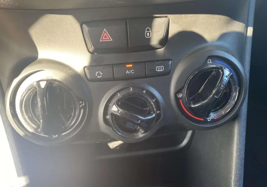 Vue rapprochée des commandes de climatisation et verrouillage central sur Peugeot 208 noire, version 2016.