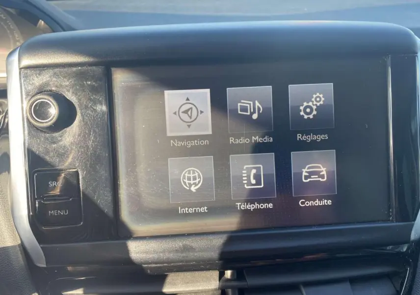 Écran tactile central de la Peugeot 208 noir, affichant les options navigation, radio, réglages et téléphone.