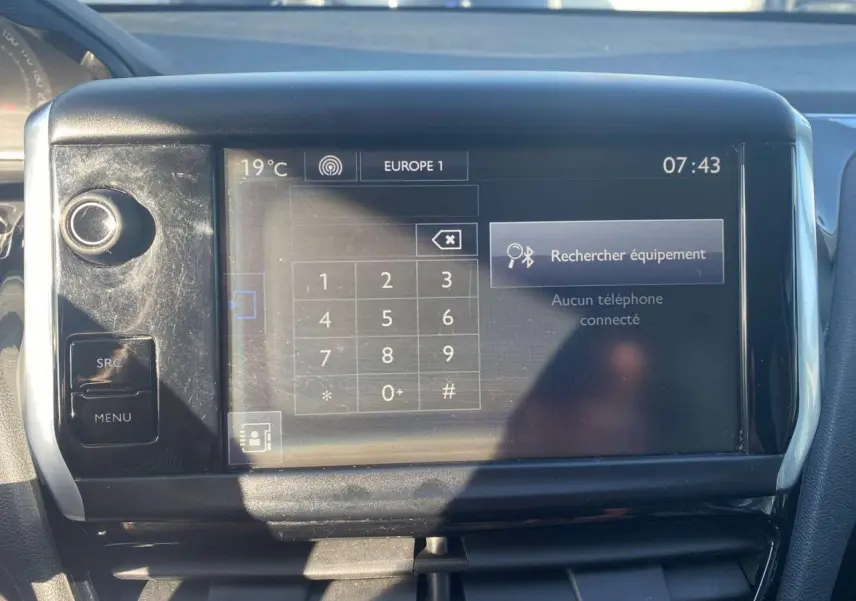 Écran tactile central de la Peugeot 208 noire montrant le menu Bluetooth avec clavier numérique, vue intérieure frontale.