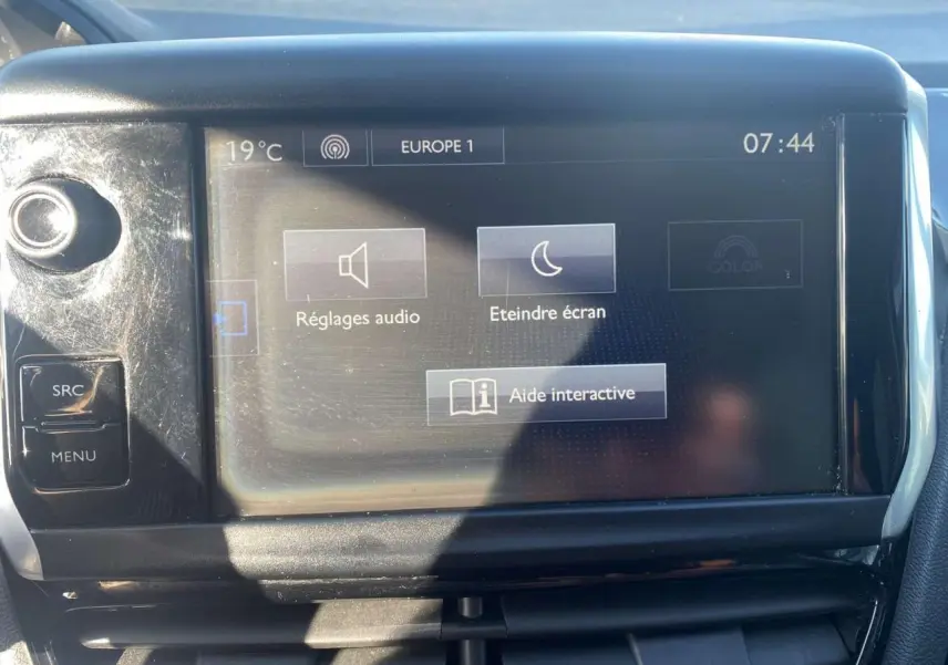 Écran tactile central de la Peugeot 208 noir, vue frontale, affichant les réglages audio et aide interactive.