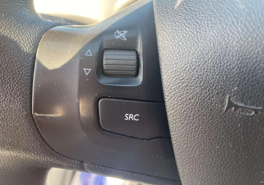 Gros plan sur les commandes audio au volant côté gauche d'une Peugeot 208 noire, version 2016.