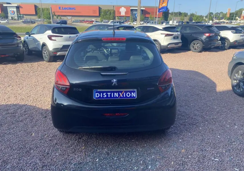 Vue arrière d'une Peugeot 208 noire 2016 avec plaque Distinxion, stationnée sur un parking en gravier.
