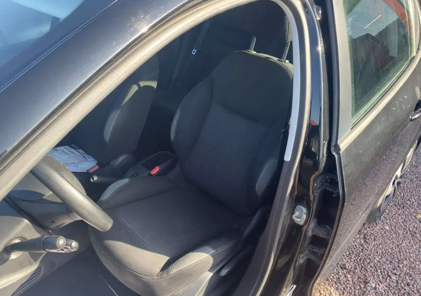 Vue intérieure côté conducteur d'une Peugeot 208 noire de 2016, montrant le siège avant et le volant multifonction.