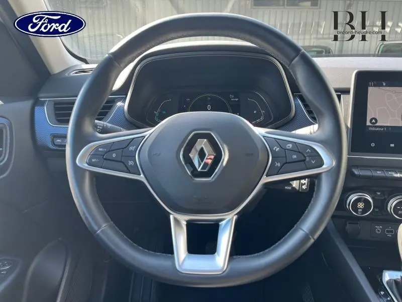 Vue centrée sur le volant noir du Renault Arkana 1.6 E-Tech 145ch Business avec tableau de bord numérique et écran tactile.