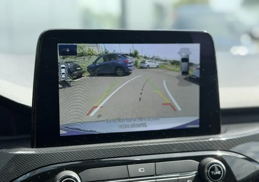 Écran tactile intérieur montrant la caméra de recul avec vue arrière d’un Ford Kuga gris Solar en stationnement.