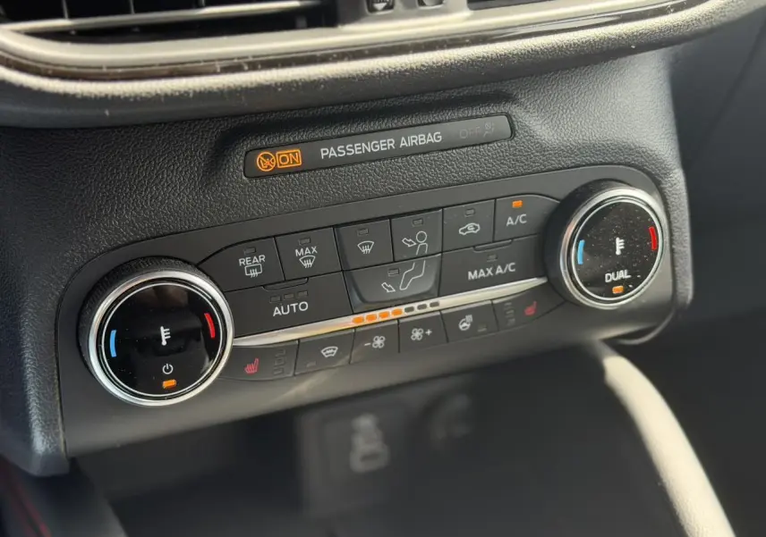 Gros plan sur la console de climatisation automatique du Ford Kuga gris Solar, avec commandes chauffantes et affichage digital.