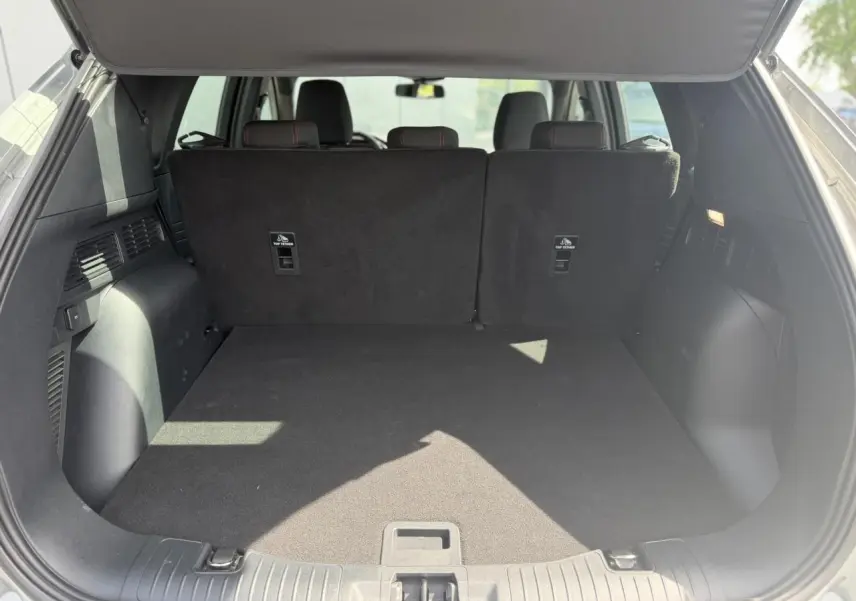 Coffre ouvert vu de l'arrière du Ford Kuga gris Solar, montrant l'espace de chargement et les dossiers des sièges arrière.
