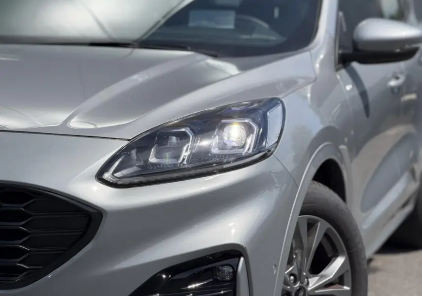 Vue 3/4 avant droit du Ford Kuga gris Solar mettant en valeur le phare Full LED et la calandre noire hexagonale.