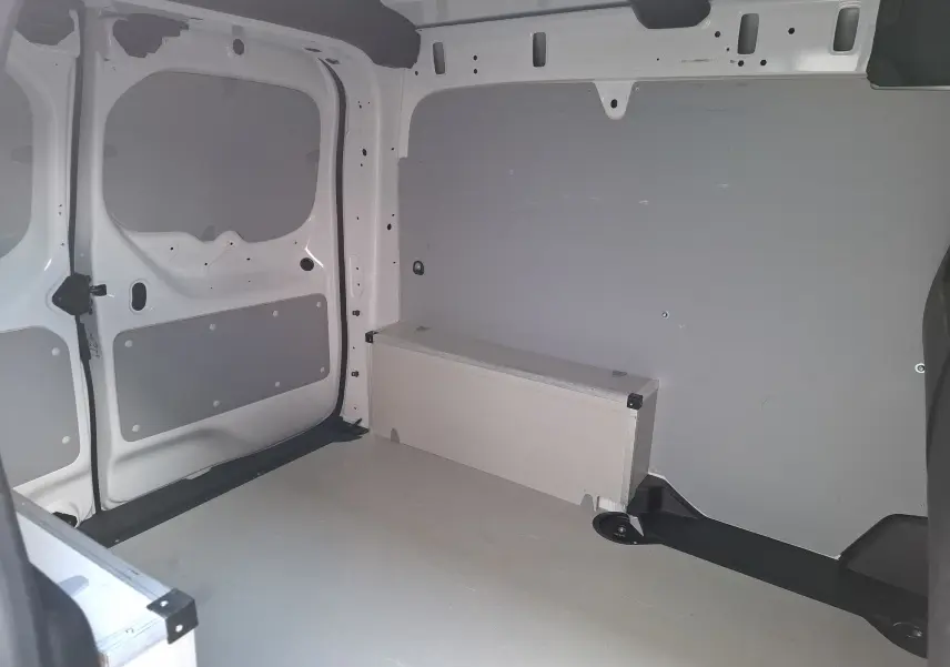 Vue intérieure de la zone de chargement du Renault Kangoo Pro blanc, montrant les parois et le plancher aménagés.