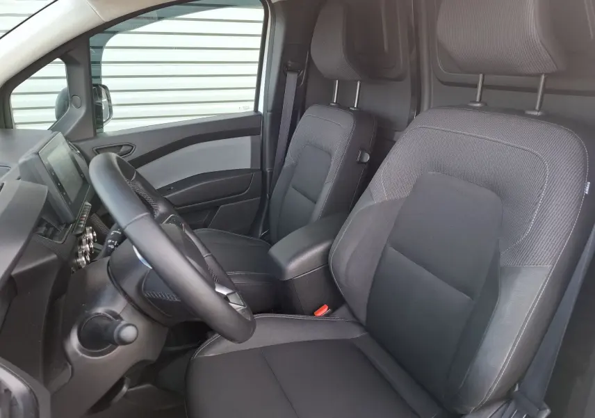 Vue intérieure côté conducteur du Renault Kangoo Pro 2025, sièges noirs avec accoudoir central et tableau de bord moderne.