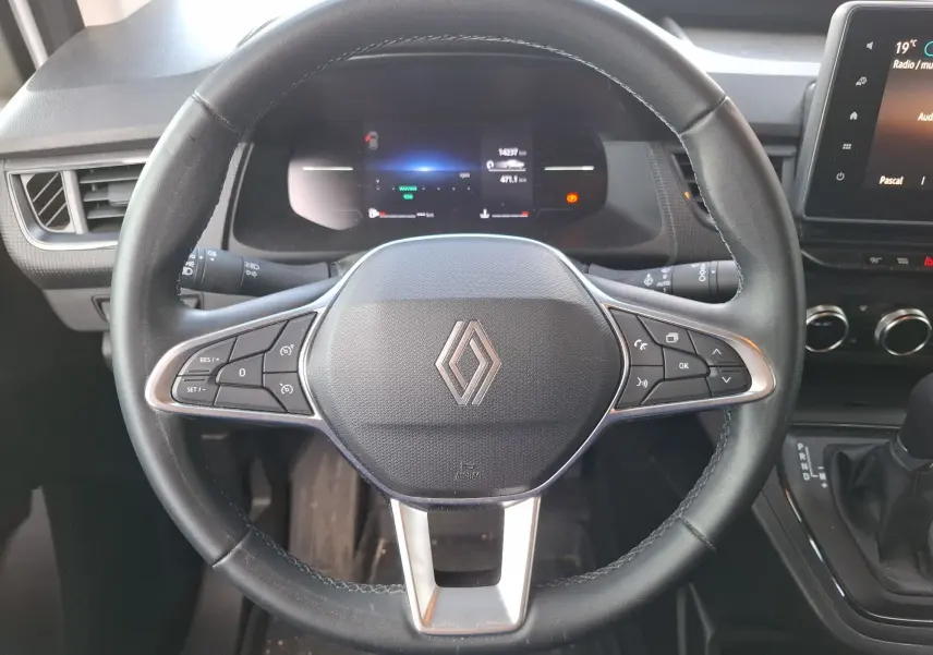 Vue rapprochée du volant noir du Renault Kangoo Pro 2025 avec commandes intégrées et tableau de bord digital.