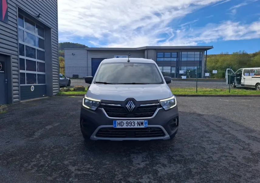 Vue de face du Renault Kangoo Pro blanc avec calandre noire et feux de jour LED allumés sur parking extérieur.