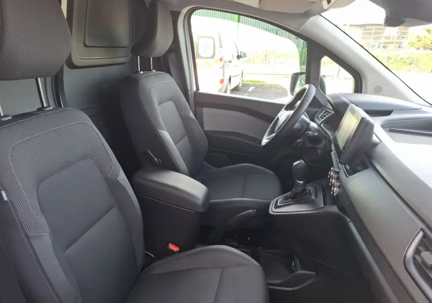 Vue intérieure côté conducteur du Renault Kangoo Pro blanc 2025, montrant sièges noirs et tableau de bord moderne.
