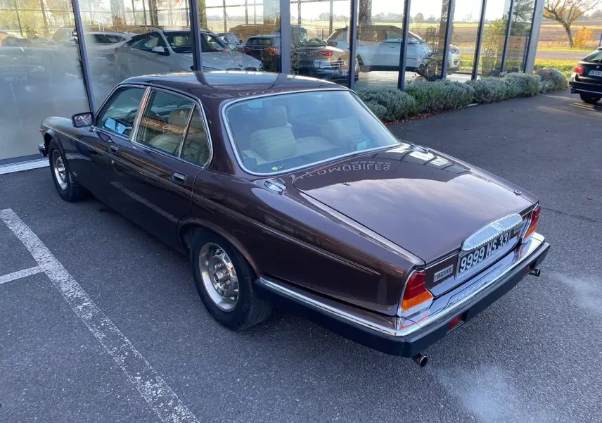 Vue 3/4 arrière droite d'une Jaguar XJ6 Série 3 4.2 Sovereign marron de 1985 avec ses chromes brillants.