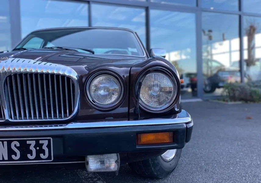 Vue de face rapprochée d'une Jaguar XJ6 Série 3 4.2 Sovereign marron avec calandre chromée et phares ronds.