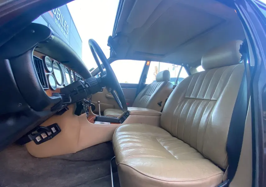 Intérieur beige cuir d'une Jaguar XJ6 Série 3 4.2 Sovereign 1985, vue côté conducteur avec tableau de bord bois.