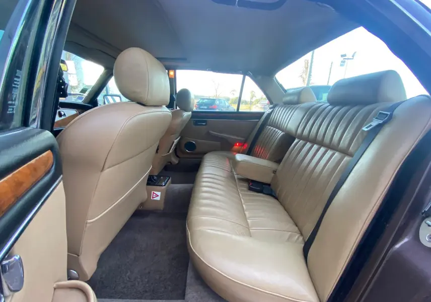 Vue intérieure arrière côté droit d'une Jaguar XJ6 Série 3 4.2 Sovereign 1985, sellerie cuir beige et boiseries apparentes.