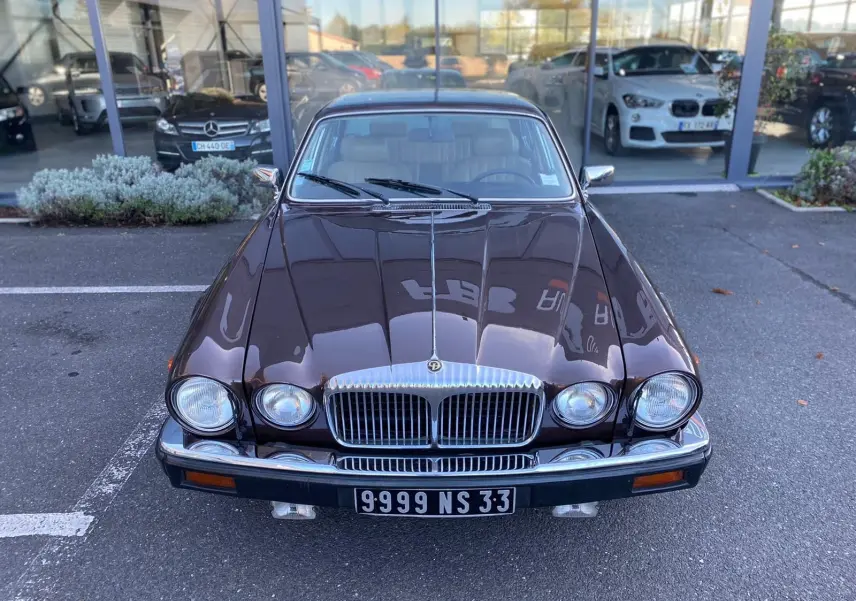 Vue avant d'une Jaguar XJ6 Série 3 4.2 Sovereign marron de 1985 avec calandre chromée et phares ronds doubles.