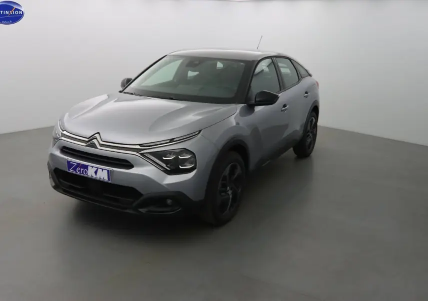 Citroën C4 gris Artense métal vue 3/4 avant droit dans un studio lumineux, jantes noires visibles.