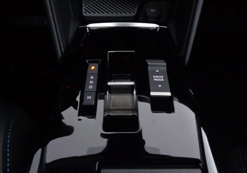 Gros plan sur la console centrale brillante de la Citroën C4 gris Artense, avec levier de vitesses automatique et bouton Drive Mode.