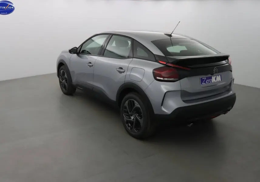 Vue 3/4 arrière droite d'une Citroën C4 2023 gris Artense métallisé avec toit noir et jantes bi-ton.