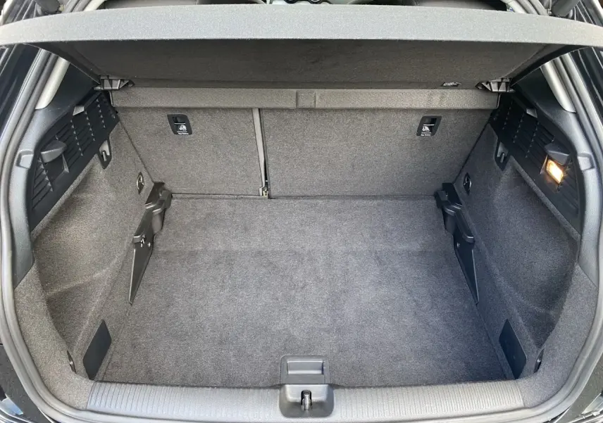 Détail du tableau de bord noir de l'Audi Q2 35 TFSI 2023 montrant la commande des phares et le levier de régulateur de vitesse.