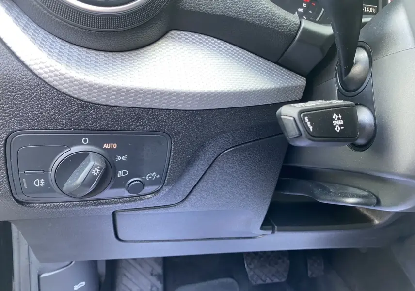 Vue rapprochée de la console centrale noire avec levier de vitesses automatique et molette de commande multimédia d'un Audi Q2.