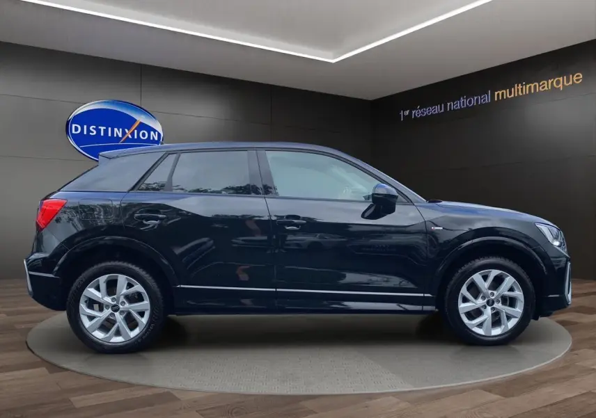 Audi Q2 noir mito vue profil côté gauche, jantes alliage 17 pouces et finition S-Line visible en showroom.