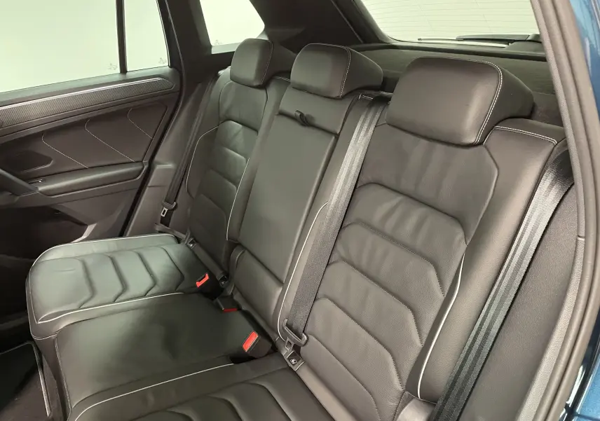 Vue intérieure côté droit montrant la banquette arrière en cuir noir avec surpiqûres contrastantes du Volkswagen Tiguan 2024.