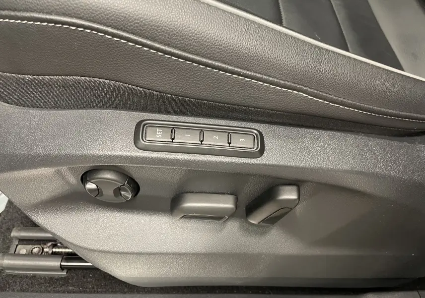 Gros plan sur les commandes de réglage électrique du siège conducteur en cuir noir du Volkswagen Tiguan Nightshade Blue 2024.