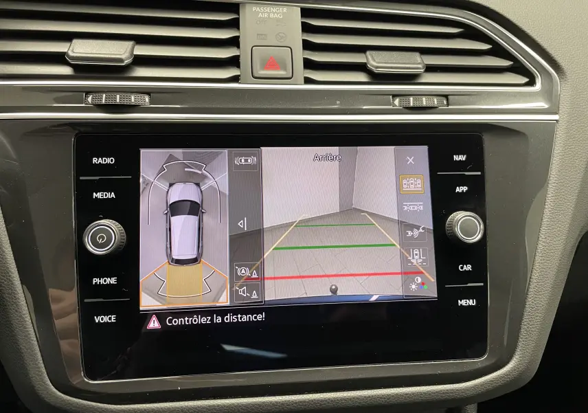 Vue rapprochée de l'écran tactile du Volkswagen Tiguan 2024 affichant la caméra de recul et l'aide au stationnement.