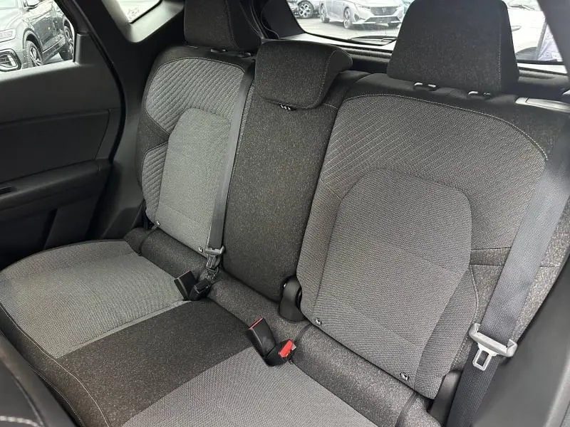 Vue intérieure montrant la banquette arrière en tissu gris et noir du Renault Captur 2025 hybride, avec ceintures de sécurité visibles.