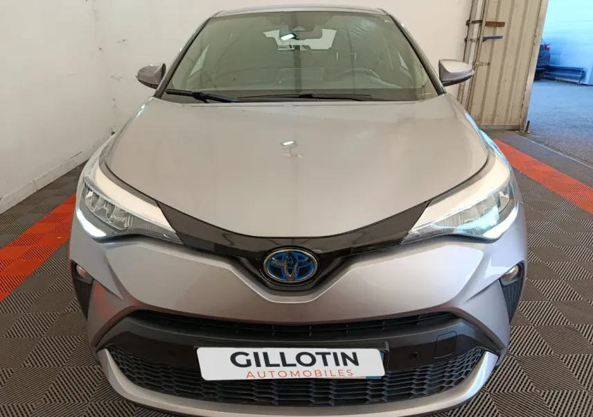 Vue avant d'un Toyota C-HR gris clair 2022 avec phares LED allumés et calandre noire distinctive.