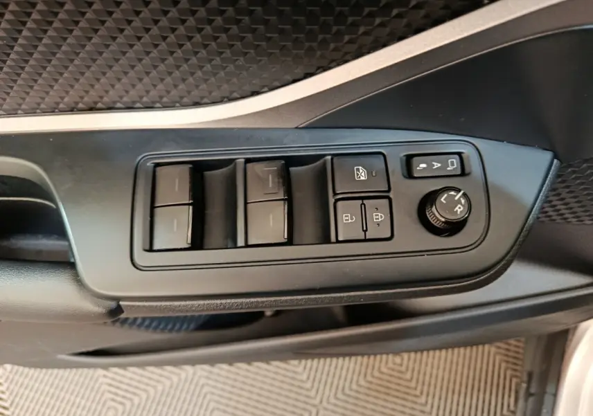 Gros plan sur les commandes de lève-vitres et réglage des rétroviseurs côté conducteur du Toyota C-HR gris clair.