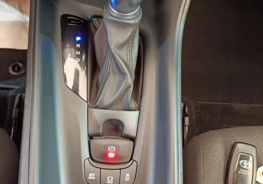 Vue plongeante sur la console centrale du Toyota C-HR hybride 2022, avec levier de vitesse et clé sur siège gris.