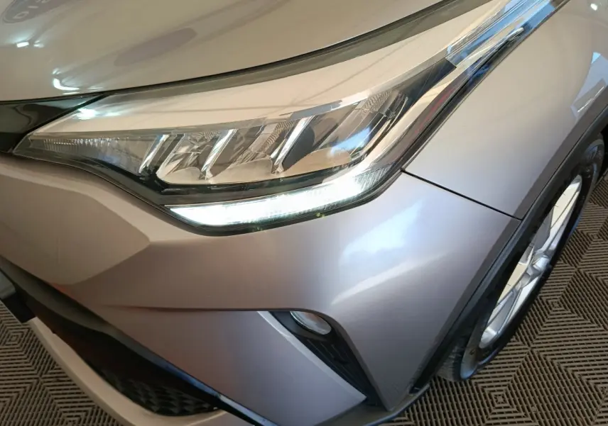 Gros plan sur le phare avant droit du Toyota C-HR gris clair 2022 avec détails LED et partie de la roue.