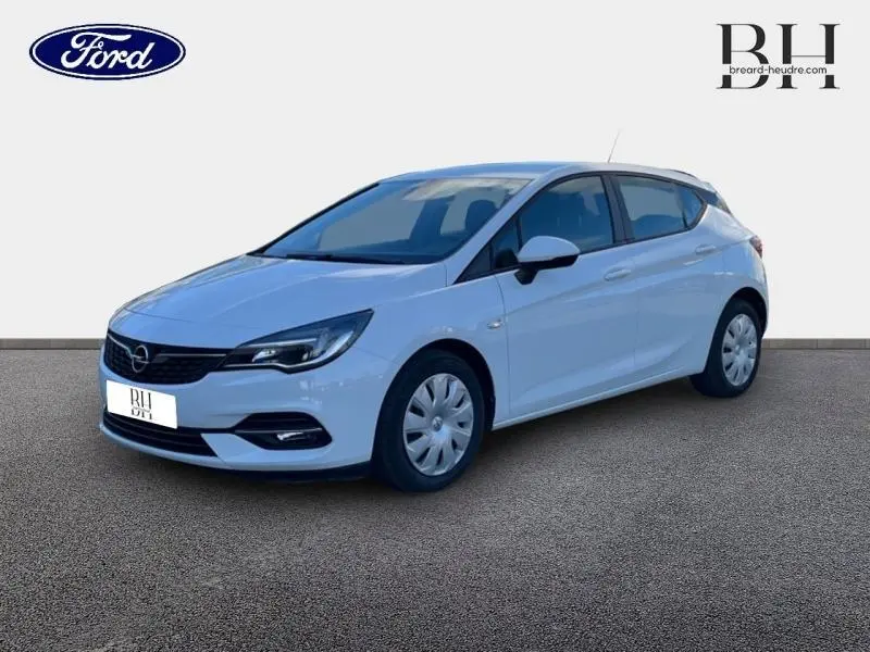 Opel Astra blanc glacier vue 3/4 avant droit, avec enjoliveurs et phares halogènes visibles.