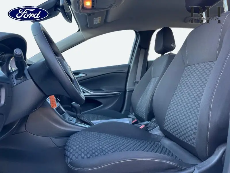 Vue intérieure côté conducteur de l'Opel Astra 1.5 D 122ch Edition Business BVA avec sièges tissu gris et volant multifonction.