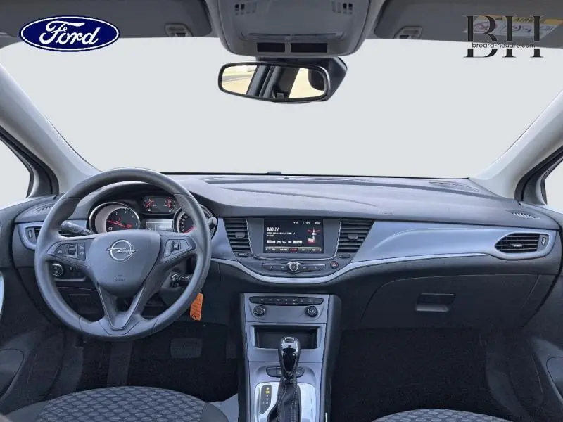 Vue intérieure frontale de l'Opel Astra blanc glacier 2020, avec tableau de bord moderne et écran tactile central.