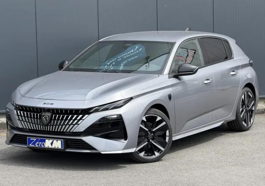 Peugeot 308 gris Artense vue 3/4 avant, avec calandre noire distinctive et jantes alliage bi-ton.